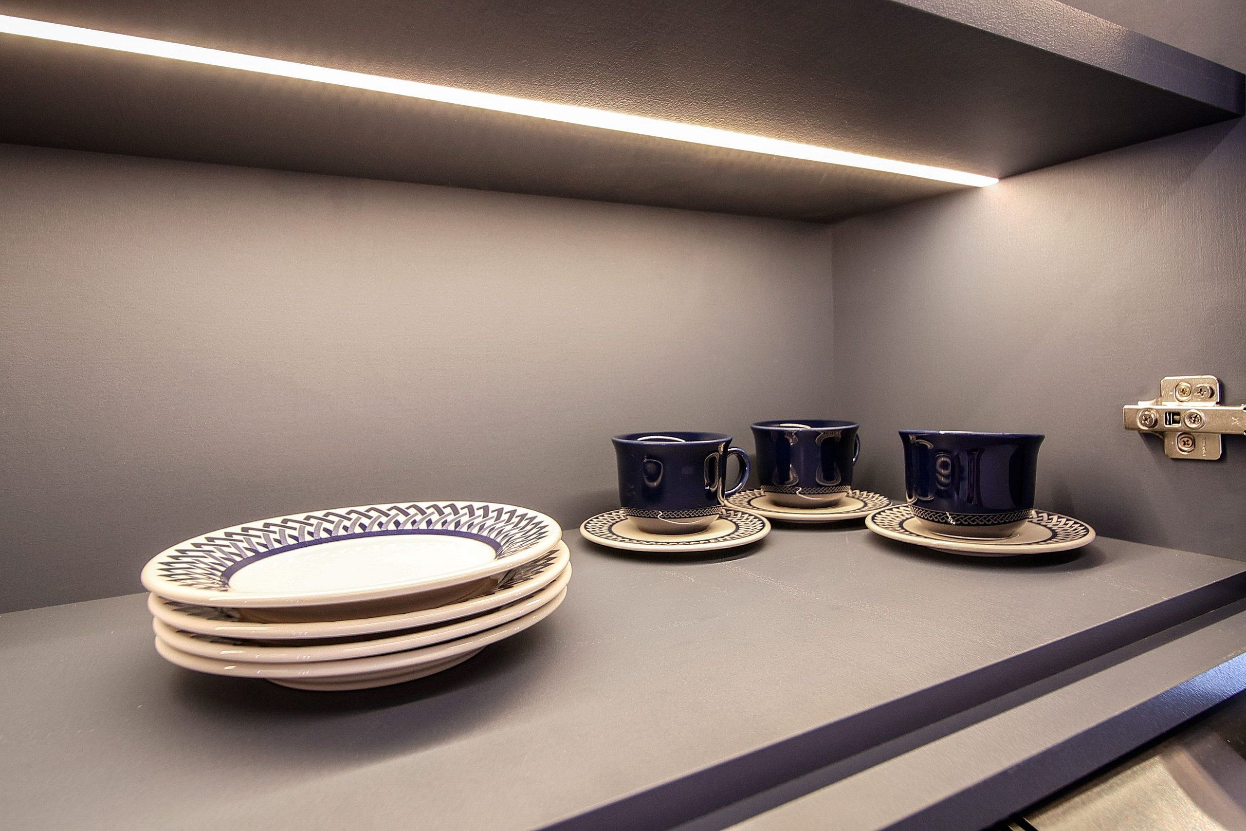 Una cocina con una pila de platos y tazas azules sobre una encimera.