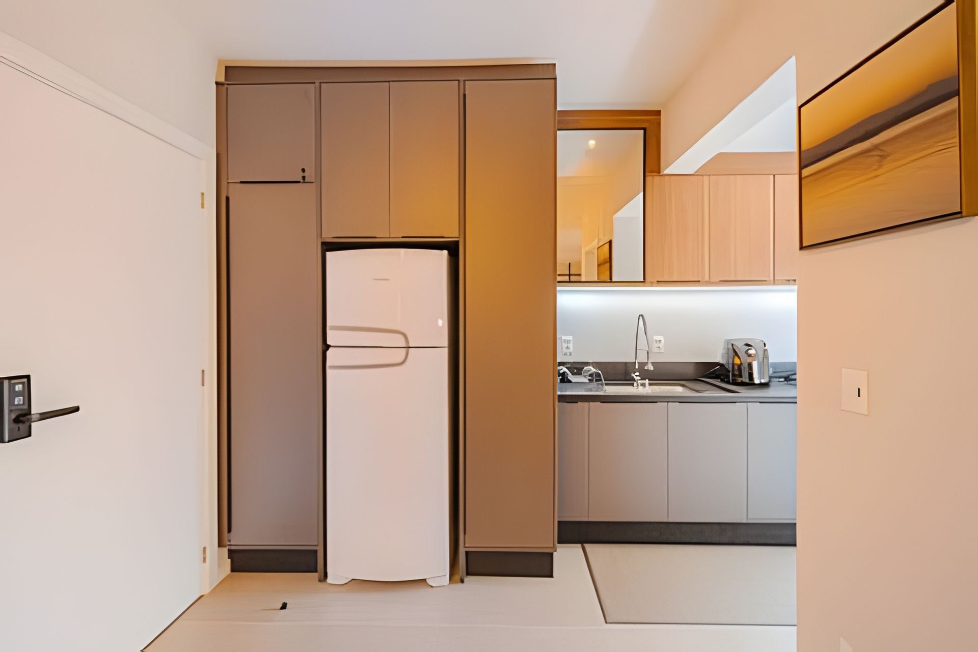 A compact kitchen with a built-in refrigerator, a sink, and a toaster.