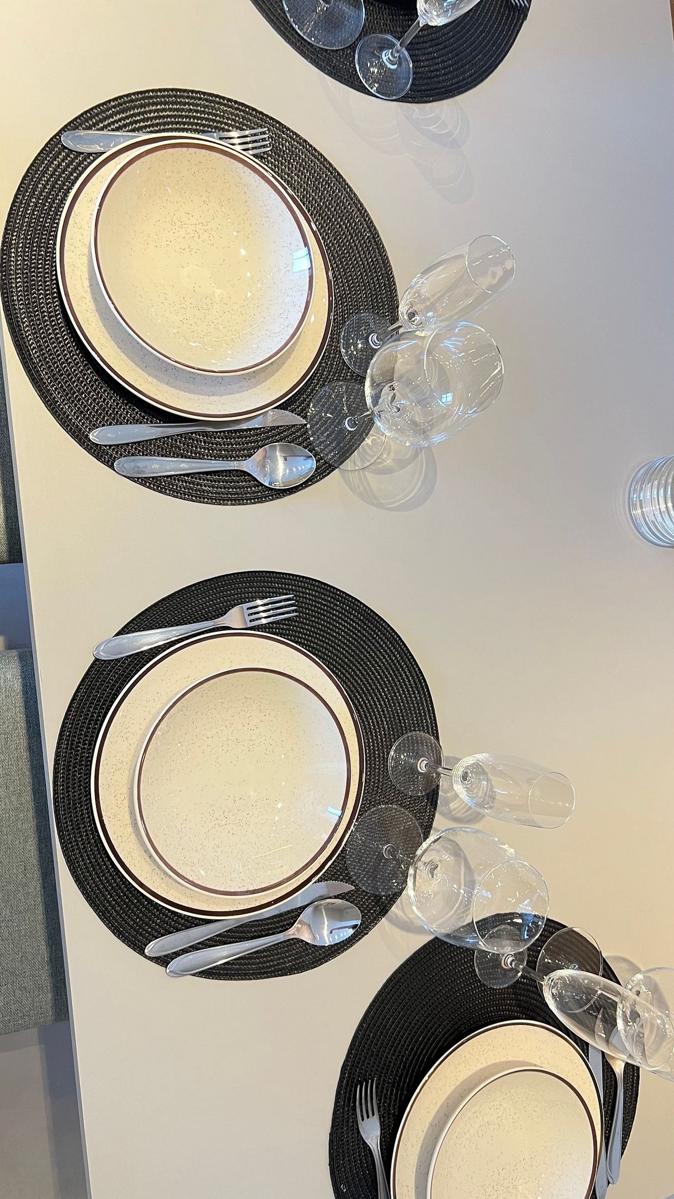 A table set with plates, cutlery, and wine glasses.