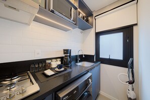 Une cuisine compacte équipée d’une cuisinière à gaz, d’une machine à café, d’un évier et d’une fenêtre.