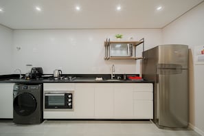 A modern kitchen with a built-in washing machine, oven, microwave, and stainless steel refrigerator. - Mingus Residencial Flipchave MIN000 (Joinville)