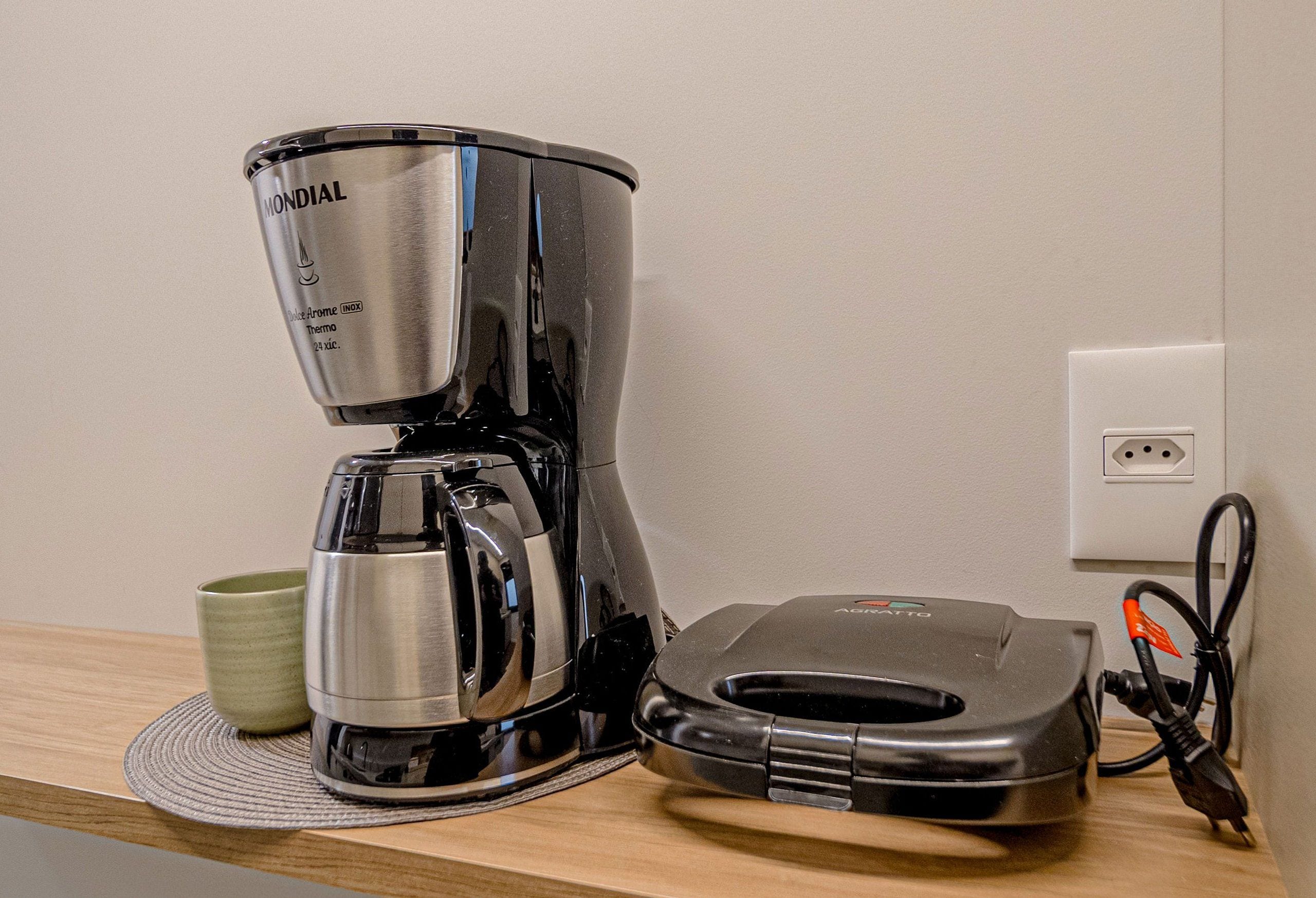 Une machine à café, une tasse et un multiprise sur une surface en bois.