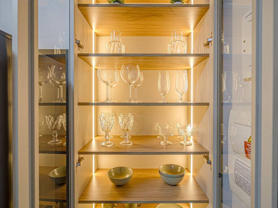A kitchen with wooden shelves and glass cabinets, containing various kitchenware and glassware.