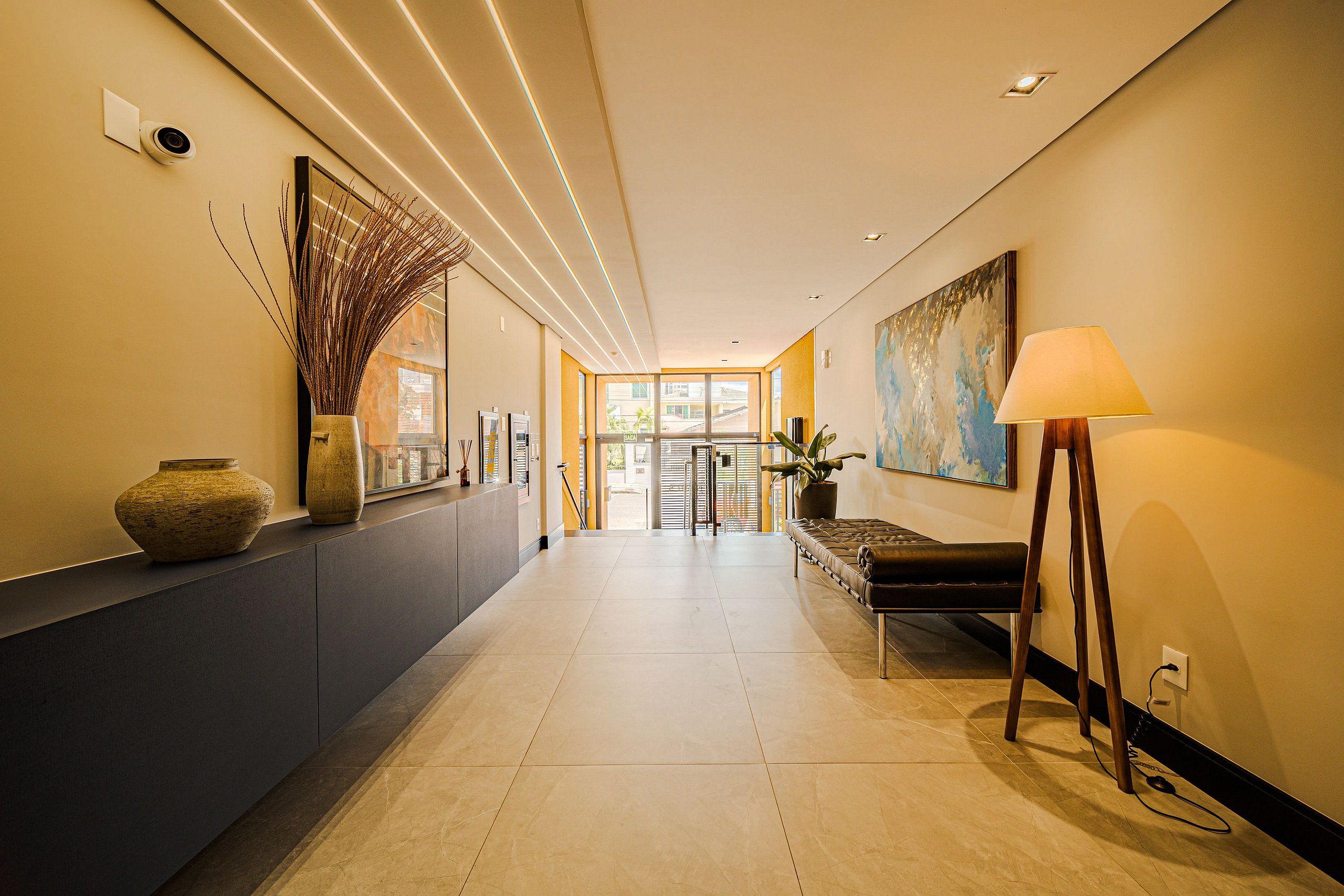 A modern hotel lobby with a long reception desk, a large painting, and a lamp.