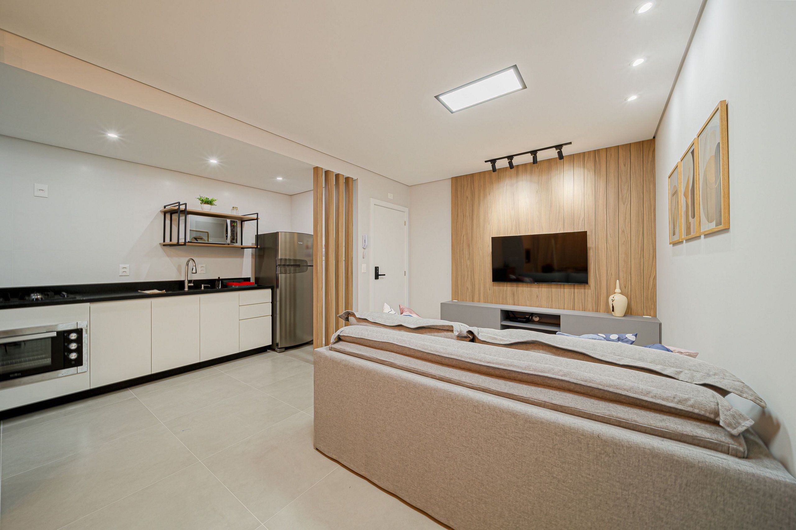 A modern kitchen with built-in appliances, a dining area with a bench, and a TV mounted on the wall.