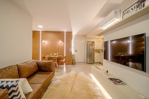 A modern living room with a leather sofa, a large flat-screen TV, and a wooden partition. - Mingus Residencial Flipchave MIN000 (Joinville)
