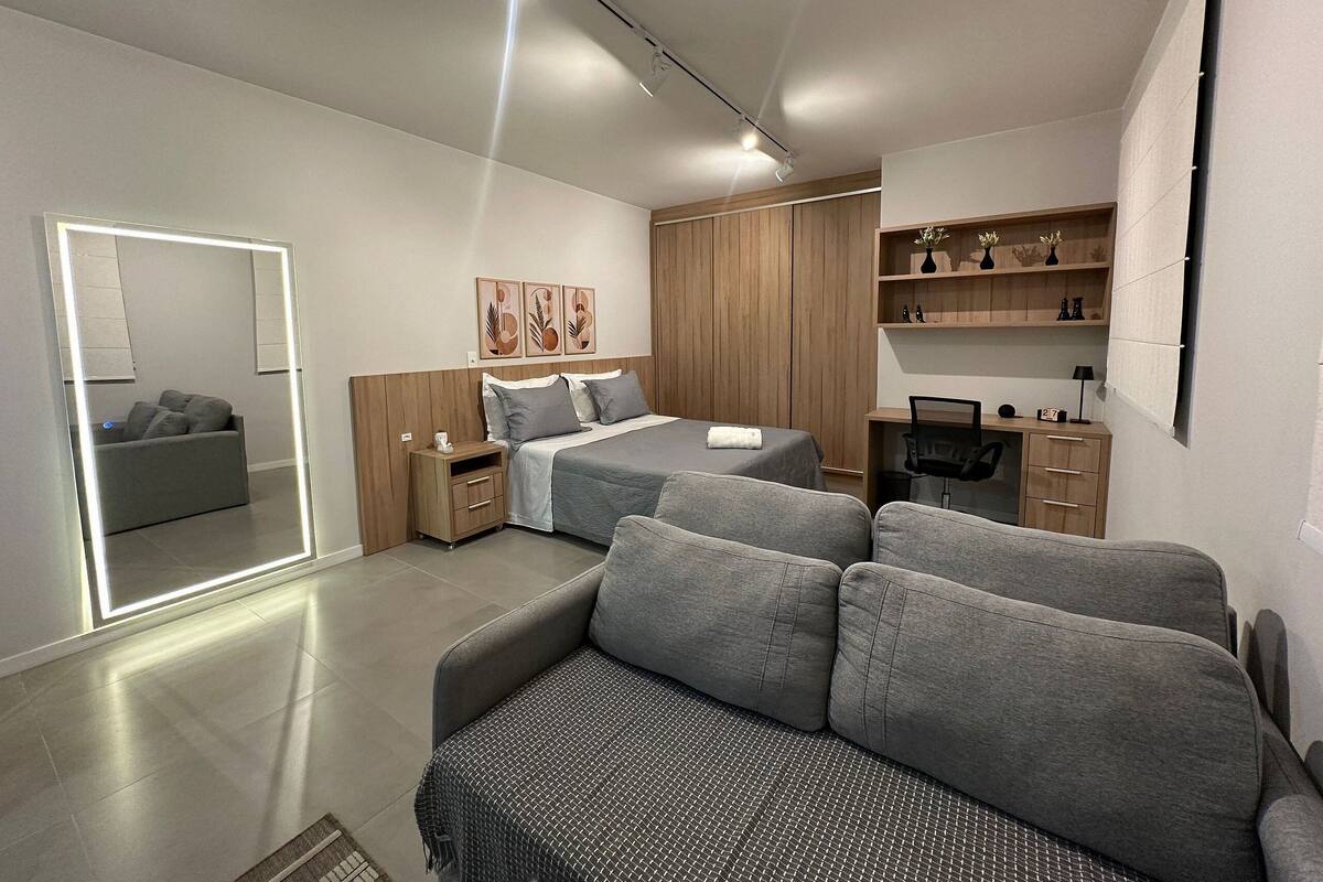 Une chambre moderne avec un lit, un canapé, un bureau et une armoire.