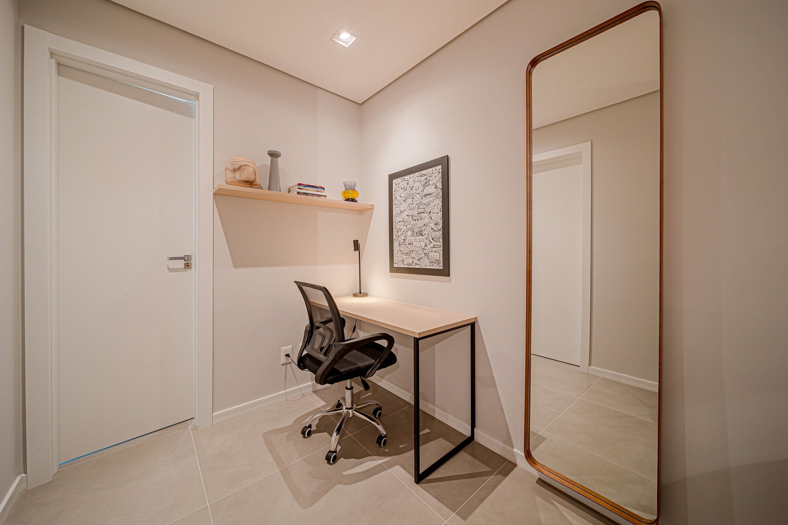 A modern room with a desk, chair, and a large mirror.