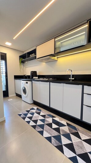 Une cuisine moderne dotée d’appareils électroménagers intégrés, d’un tapis à motifs noir et blanc et d’un plan de travail noir.