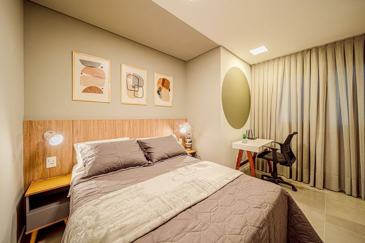 Une chambre à coucher comprenant un lit, des tables de chevet, un bureau, une chaise et des œuvres d’art accrochées au mur.