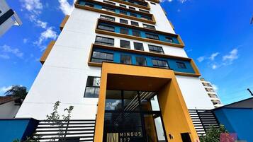 A multi-story building with a modern architectural design, featuring a prominent entrance with a glass door and a sign that reads 'MINGUS 897'.