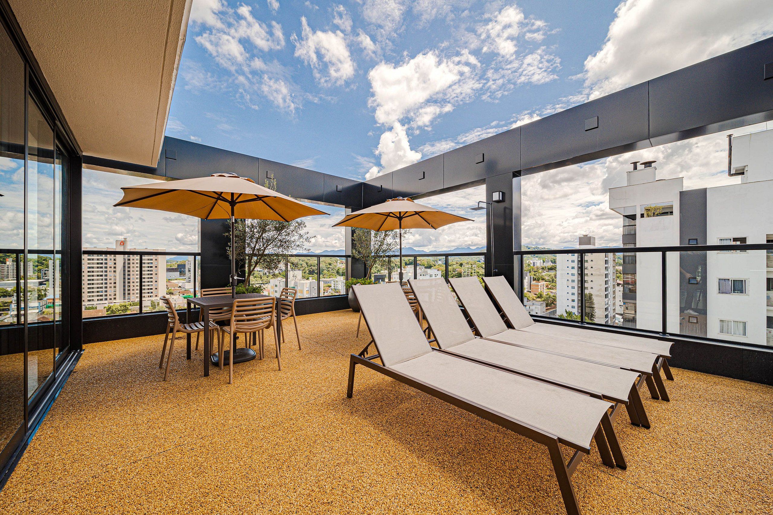 A rooftop terrace with lounge chairs, a table, and umbrellas.