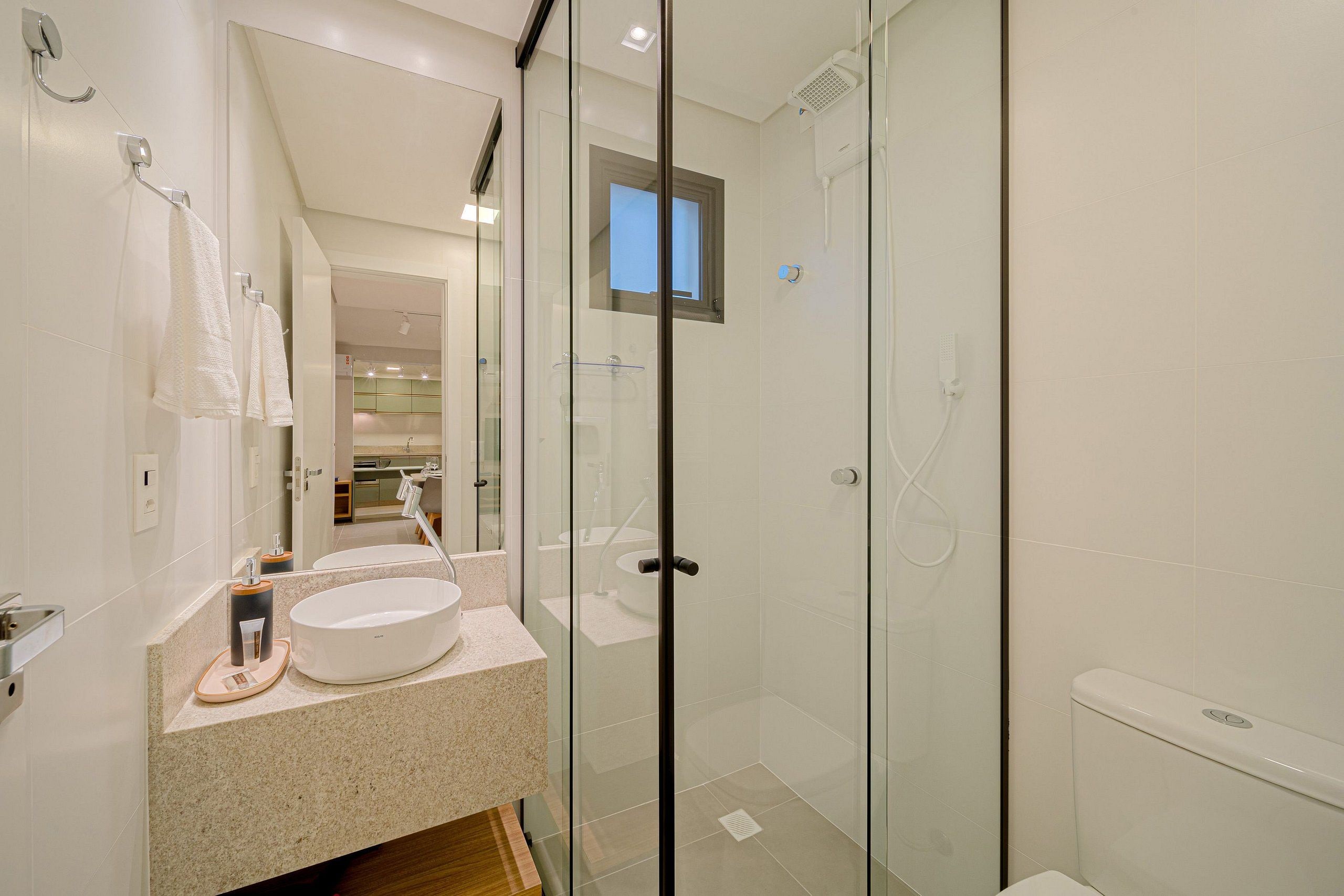 Un baño moderno con cabina de ducha de vidrio, un espejo grande y encimera de granito.