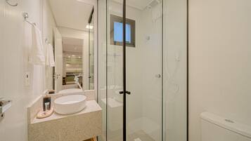 Un baño moderno con cabina de ducha de vidrio, un espejo grande y encimera de granito.