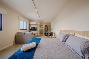 A bedroom with a bed, a sofa, a dining table, and a kitchen area. - Mingus Residencial Flipchave MIN000 (Joinville)