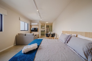Um quarto com cama, sofá, mesa de jantar e área de cozinha.