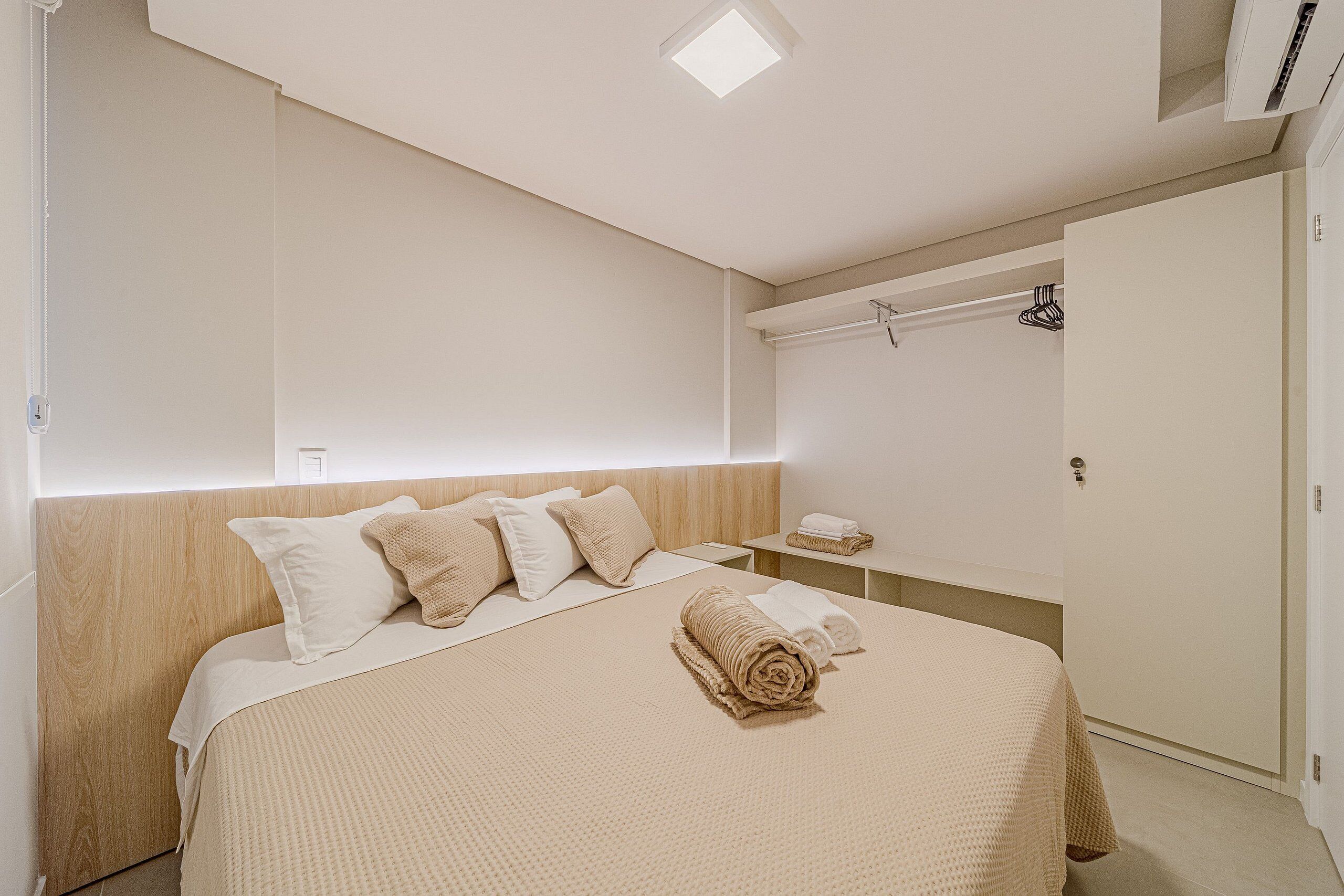 A hotel room with a bed, a nightstand, a towel, a wardrobe, and a ceiling light.