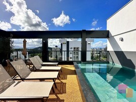 Uma área de piscina no terraço com espreguiçadeiras e vista para a cidade.