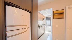 Een moderne keuken met een witte koelkast, houten kastjes en uitzicht op de eetruimte.