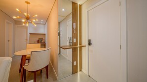 Een moderne hotelkamer met een zithoek, een spiegel, een houten accentmuur en een telefoon aan de wand.