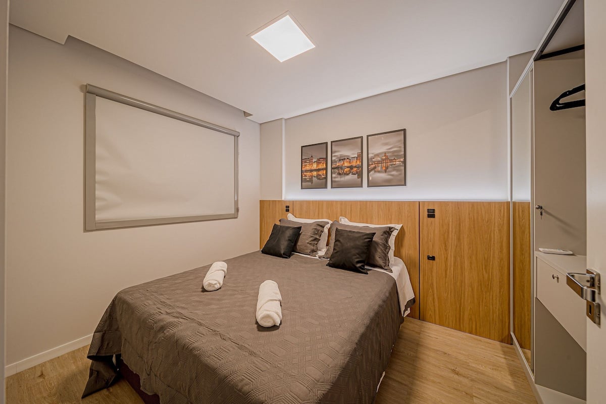 Une chambre d’hôtel avec un lit, une armoire, un miroir et un luminaire au plafond.