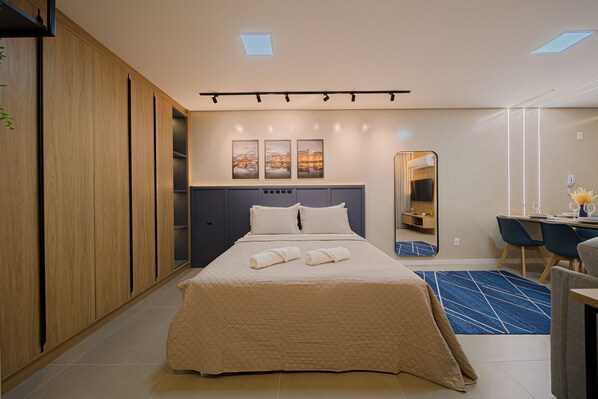 A modern hotel room with a large bed, a desk, and a mirror. - Mingus Residencial Flipchave MIN000 (Joinville)
