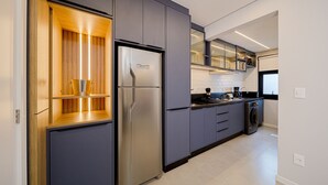 Een moderne keuken met een inbouwkoelkast, een wasmachine en een magnetron.