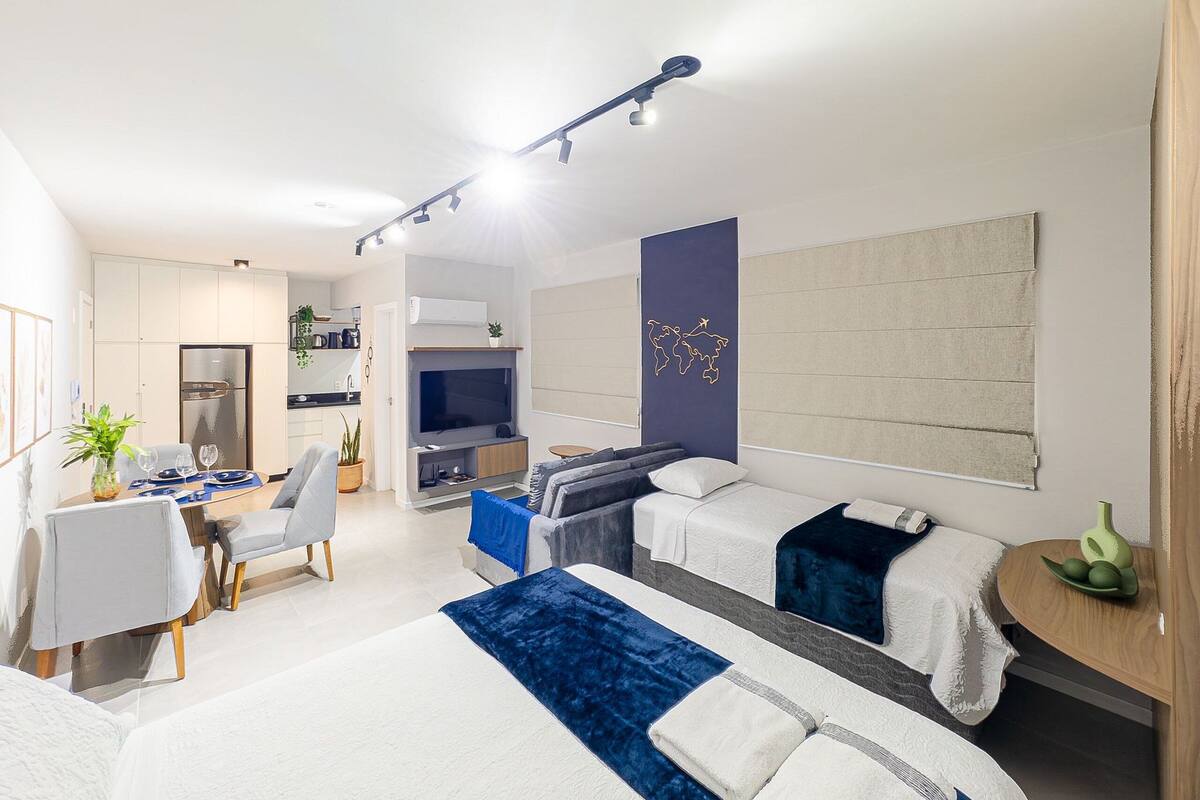 Une chambre d’hôtel moderne équipée d’un lit, d’un bureau, d’une chaise, d’une télévision et d’une grande fenêtre.