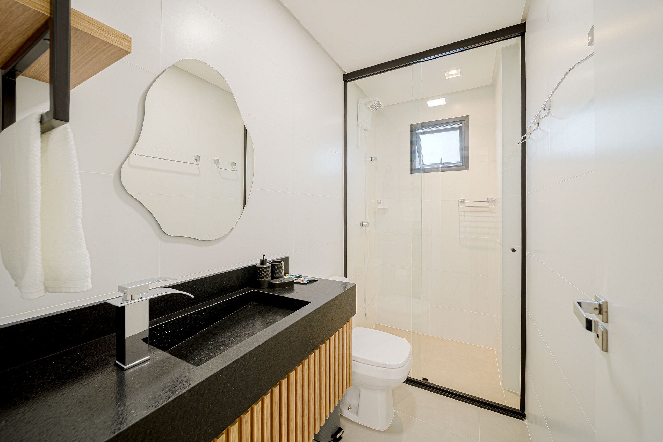Een moderne badkamer met een zwart wastafel, wit toilet en een glazen douchecabine.
