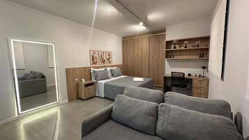 A modern bedroom with a bed, a sofa, a desk, and a wardrobe.