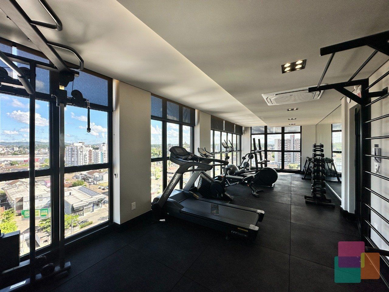 A gym with treadmills, weights, and a large window offering a city view.