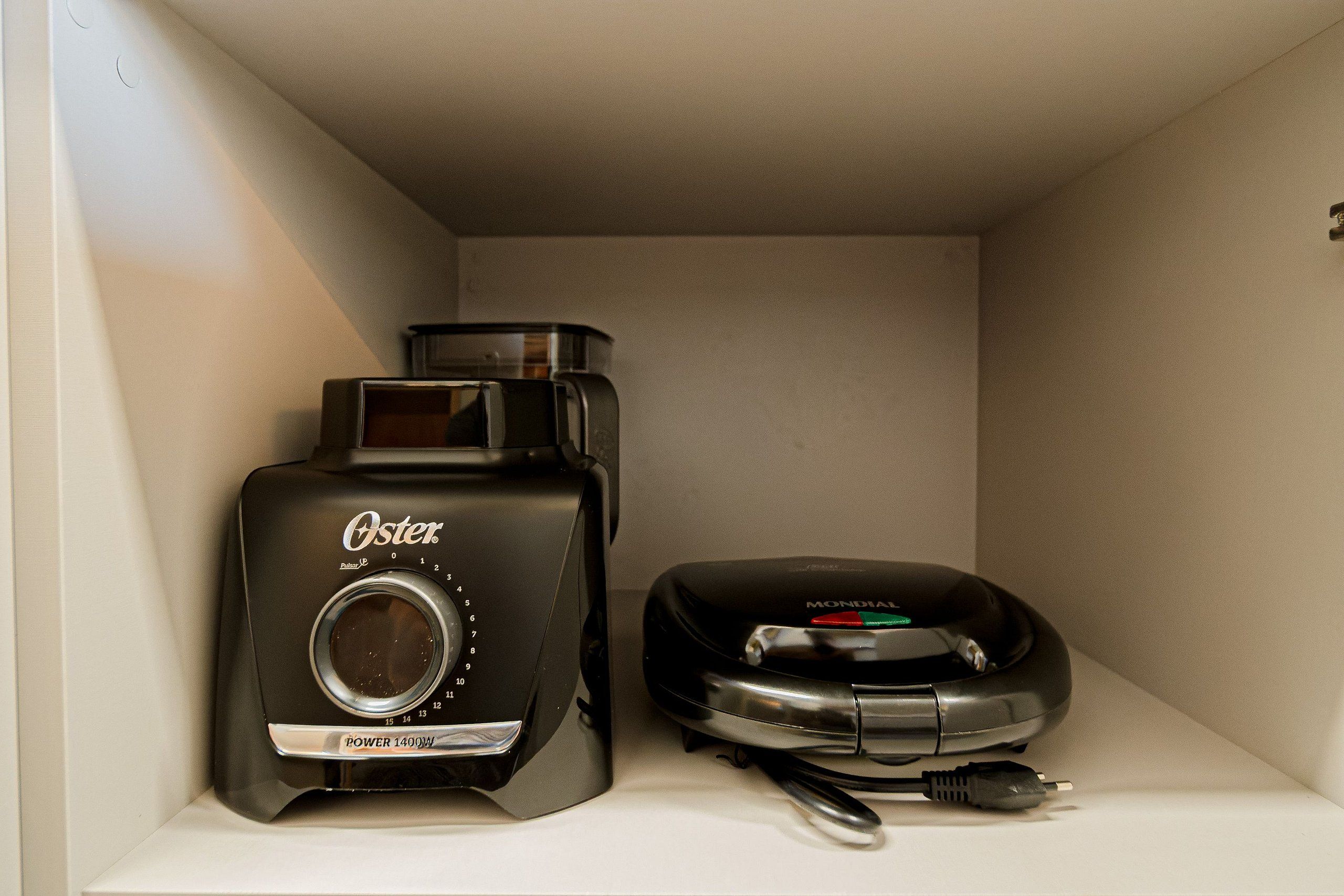 Une étagère avec une vieille cafetière Oster et un téléphone Mondial.