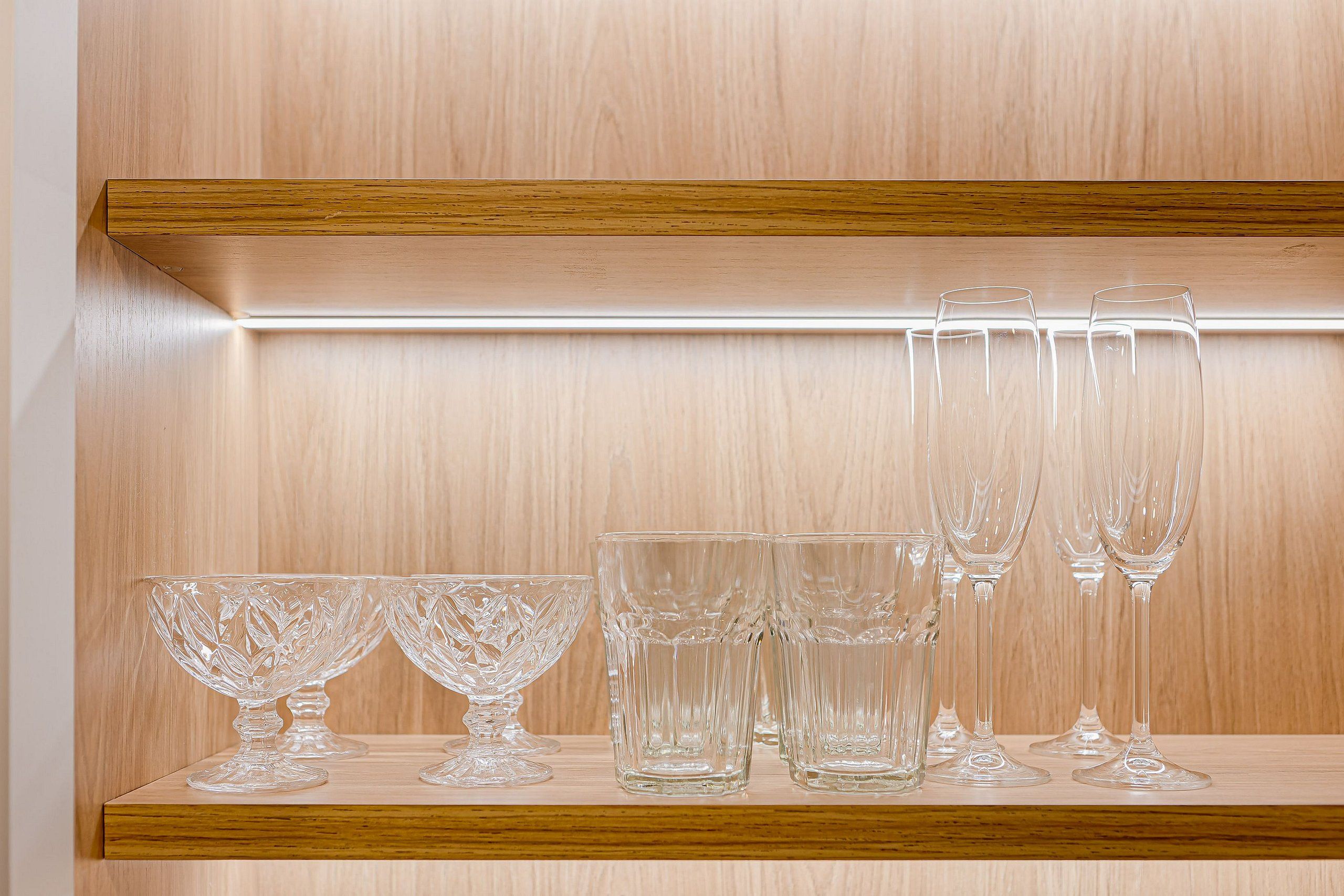 A wooden shelf with various clear glassware.