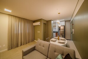 Un salon moderne avec un canapé, une table à manger et un coin cuisine en arrière-plan.