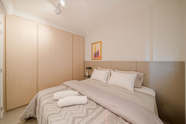 A bedroom with a bed, a wardrobe, a nightstand, and a framed picture on the wall. - Mingus Residencial Flipchave MIN000 (Joinville)