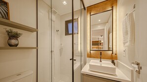 A modern bathroom with a glass shower enclosure, a white sink, and a wooden-framed mirror. - Mingus Residencial Flipchave MIN000 (Joinville)