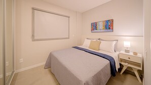 Een slaapkamer met een bed, een nachtkastje, een kunstwerk aan de muur en een schuifdeur.