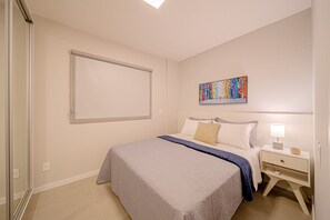 Un dormitorio con cama, mesita de noche, una obra de arte en la pared y una puerta corredera.