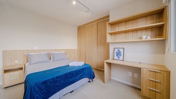 Un dormitorio con cama, mesitas de noche, escritorio y estanterías empotradas.