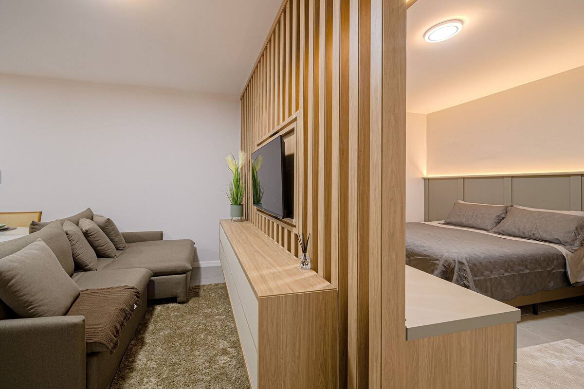 Une chambre d’hôtel moderne équipée d’un canapé, d’une télévision, d’un lit et d’une cloison en bois.