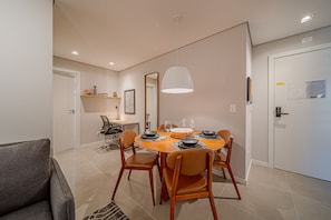 A dining area with a round table, chairs, a hanging light, and a door with a mirror and papers. - Mingus Residencial Flipchave MIN000 (Joinville)