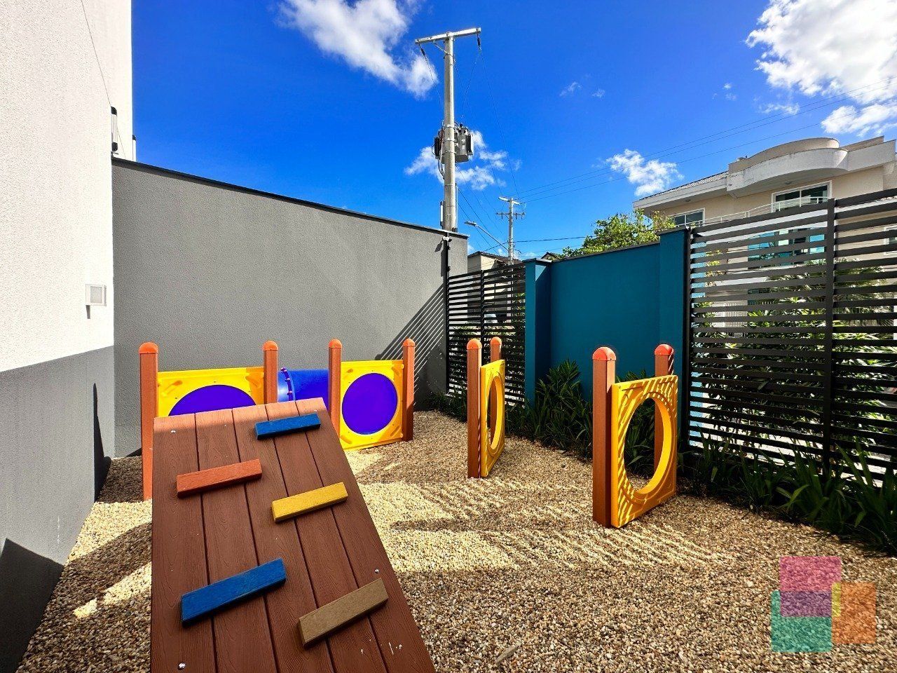 Um parquinho infantil com escorrega de madeira, estruturas de escalada e piso emborrachado.