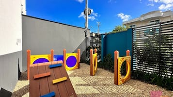 Um parquinho infantil com escorrega de madeira, estruturas de escalada e piso emborrachado.