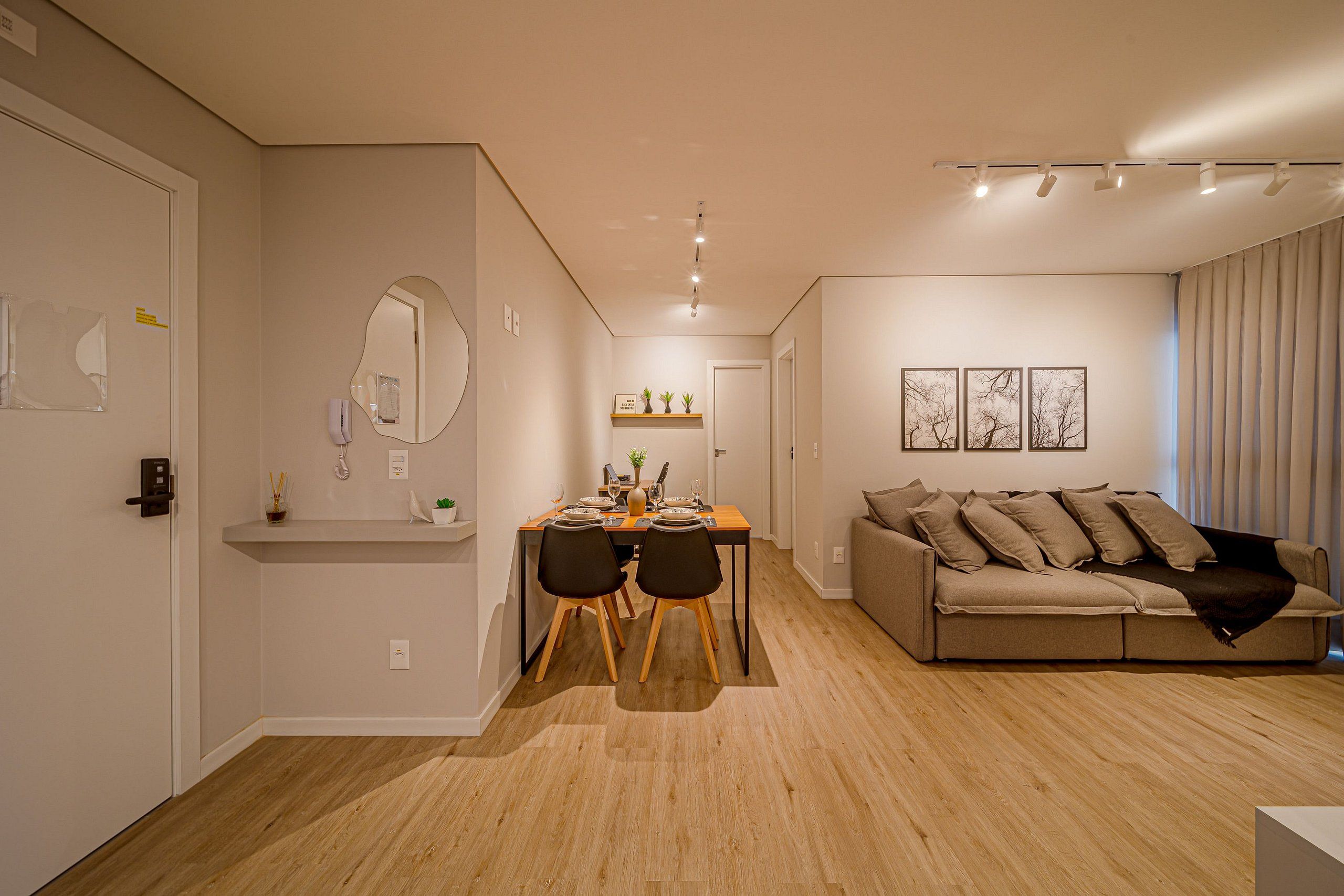 Un salon moderne avec un canapé, un coin repas comprenant une table et des chaises, et un couloir menant à une autre pièce.