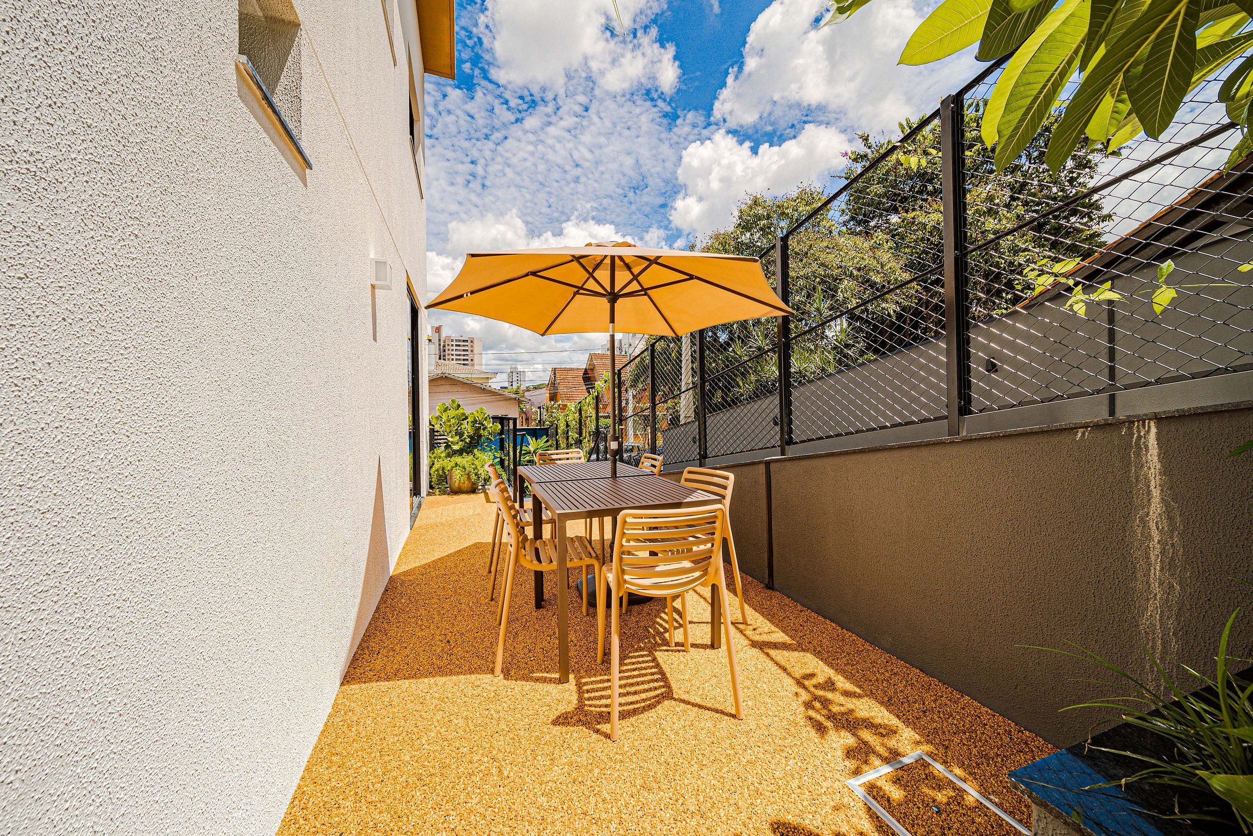 An outdoor patio with a table and chairs, a yellow umbrella, and a view of the cityscape.