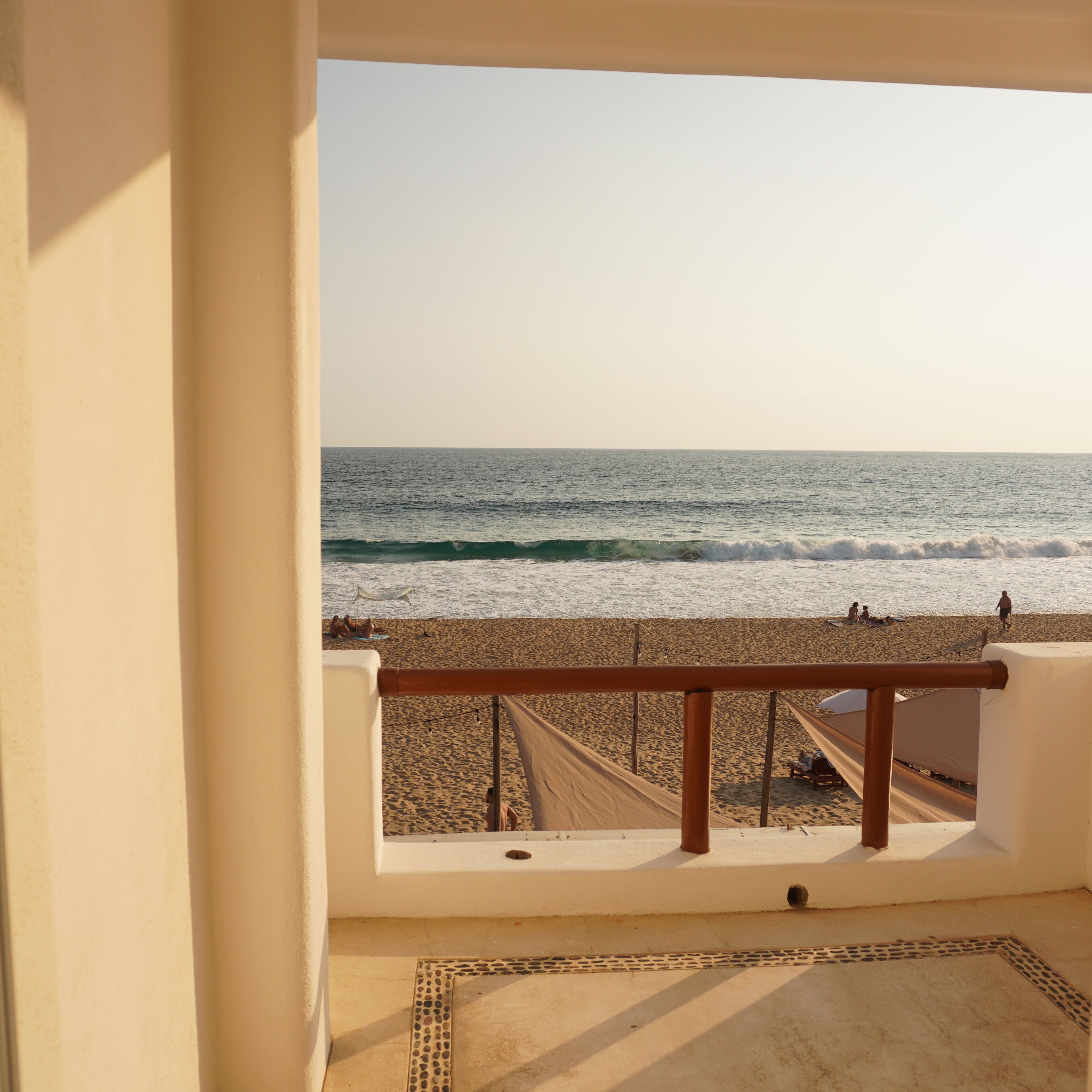 A balcony with a view of the beach and ocean.