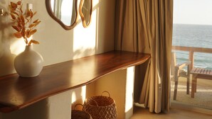 A room with a wooden console table, two wall mirrors, a vase with dried flowers, and a view of the sea through a window with curtains. - Hotel Estrella de Mar (San Pedro Pochutla)
