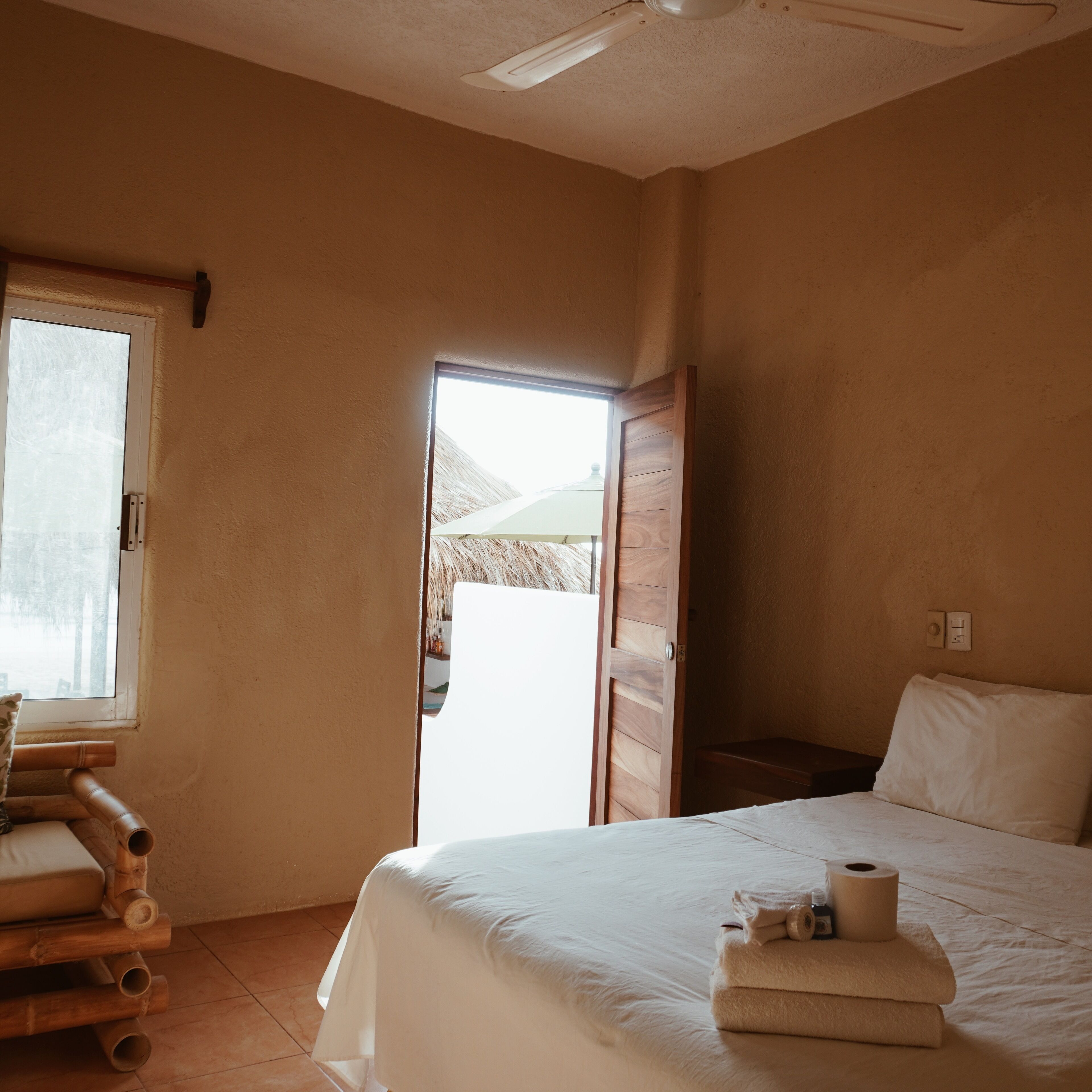Een slaapkamer met een bed, een raam, een deur en een plafondventilator.