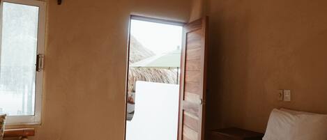 A bedroom with a bed, a window, a door, and a ceiling fan.