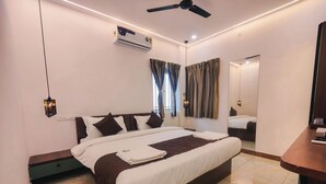 A modern hotel room with a large bed, an air conditioning unit, a ceiling fan, and a mirror. - Nova Grande' (Hosur)